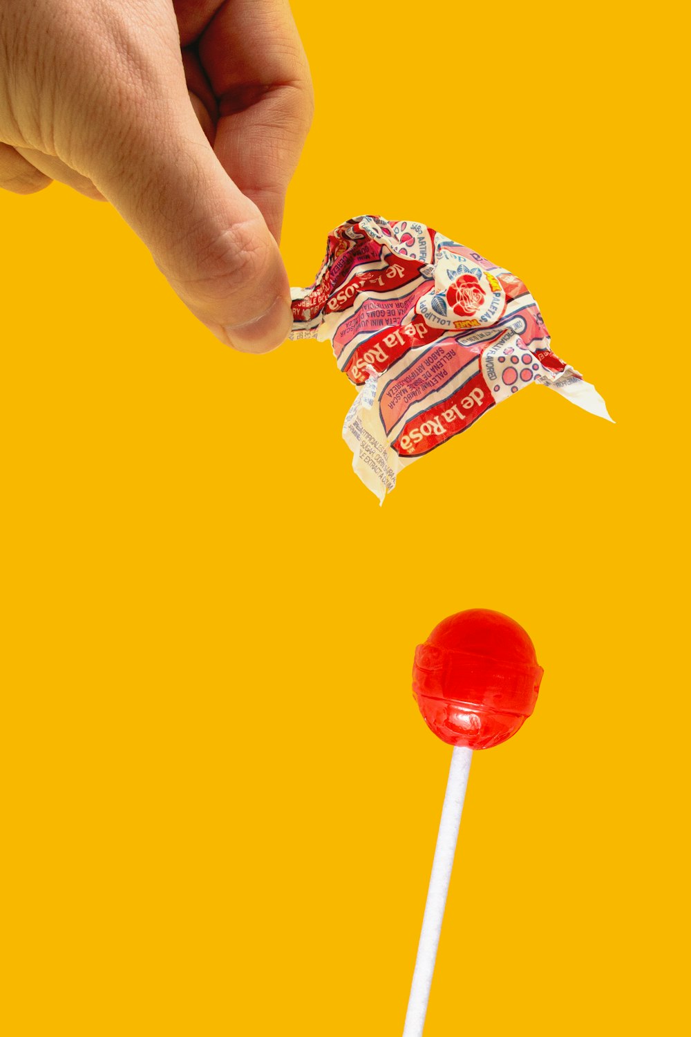 person holding red lollipop with blue and white candy wrapper