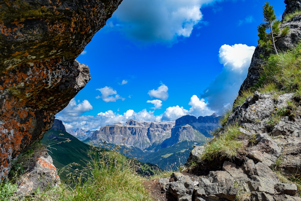 green grass and brown rocky mountain under blue sky during daytime