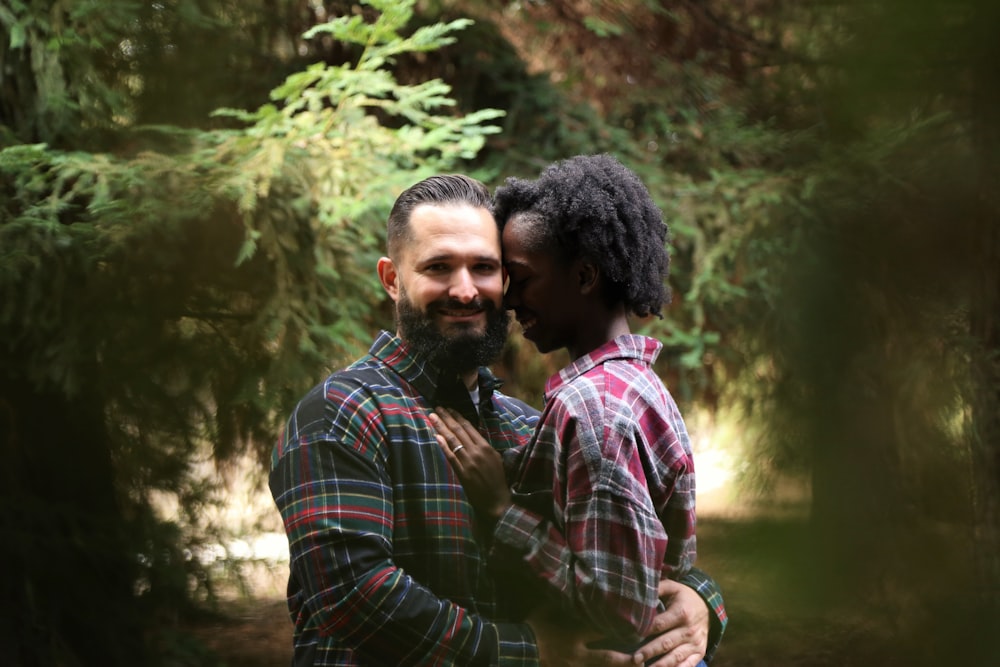 man and woman kissing near green trees during daytime