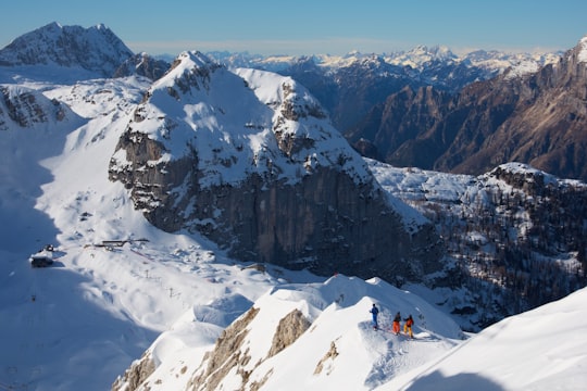 person in red jacket and black pants sitting on snow covered mountain during daytime in Bovec Slovenia