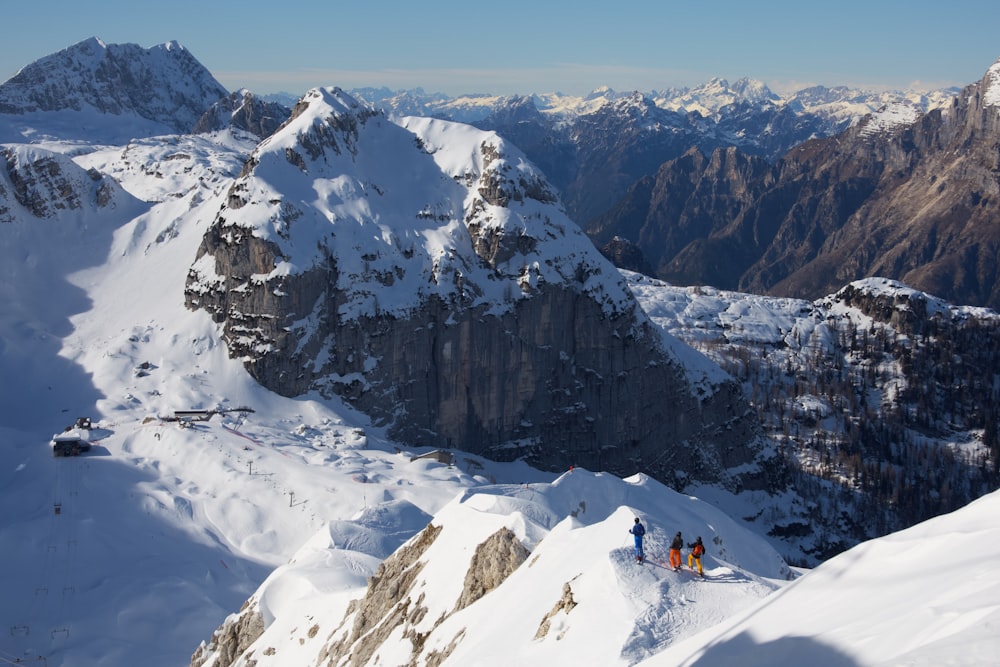 Person in roter Jacke und schwarzer Hose, die tagsüber auf einem schneebedeckten Berg sitzt