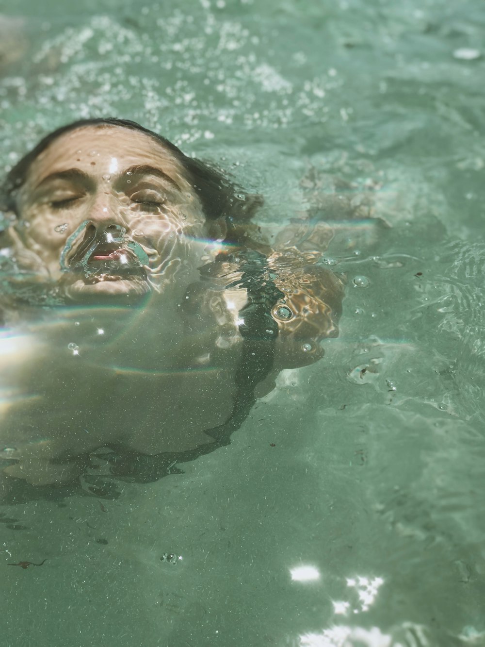 woman in water with blue and green goggles