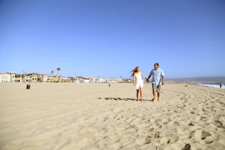 man and woman walking on beach during daytime