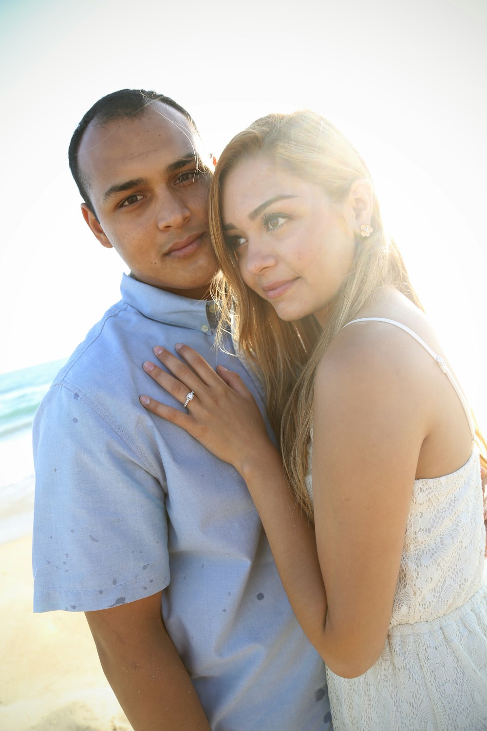 man in blue dress shirt hugging woman in white sleeveless dress