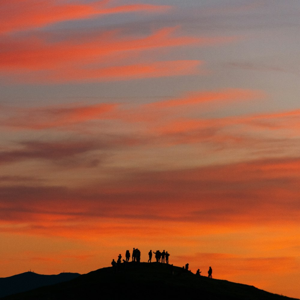 silhouette of people on top of mountain during sunset