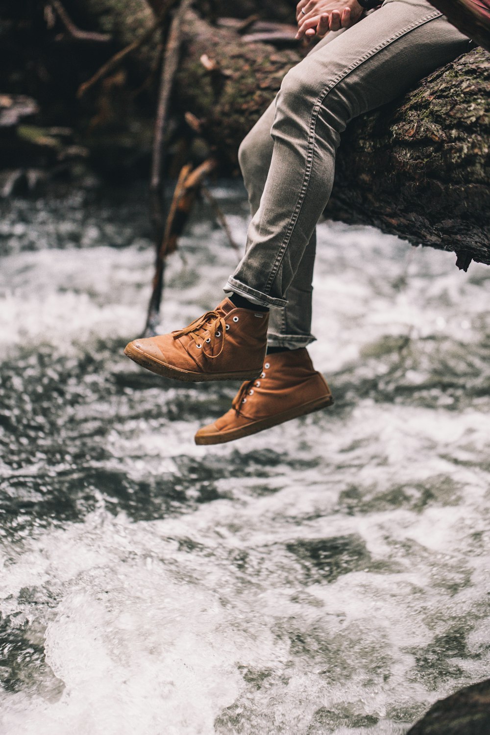 person in brown leather boots standing on rock in front of water