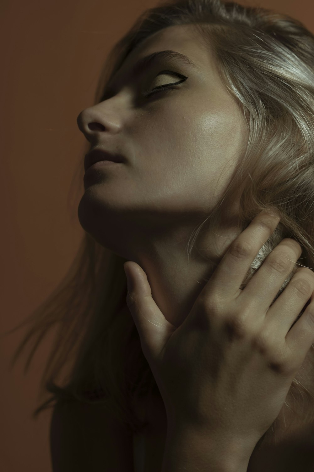 woman with blonde hair touching her face