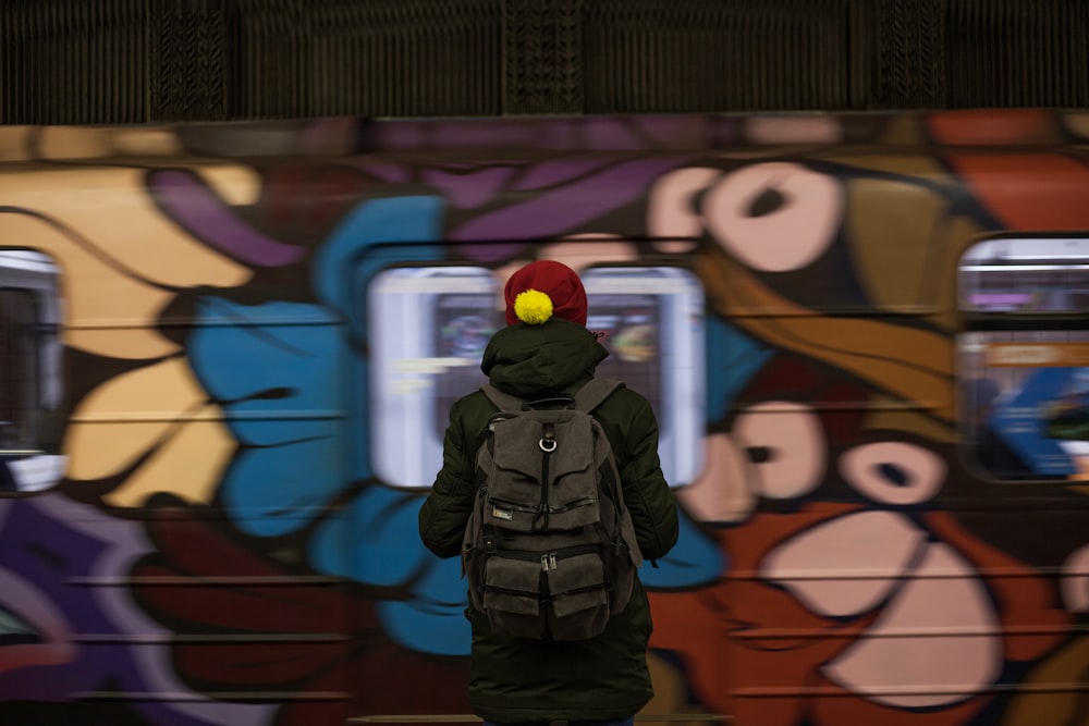 man in black jacket standing beside wall