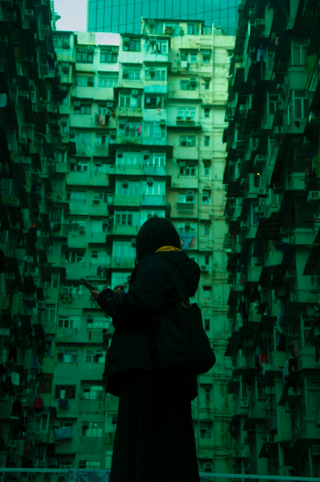 person in black hoodie standing on green and blue lighted building