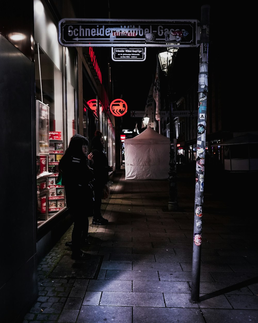 검은 재킷을 입은 남자가 밤 시간 동안 보도를 걷고 있다