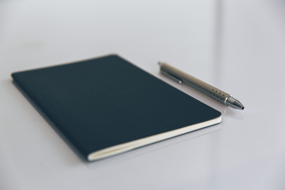 blue book beside white pen