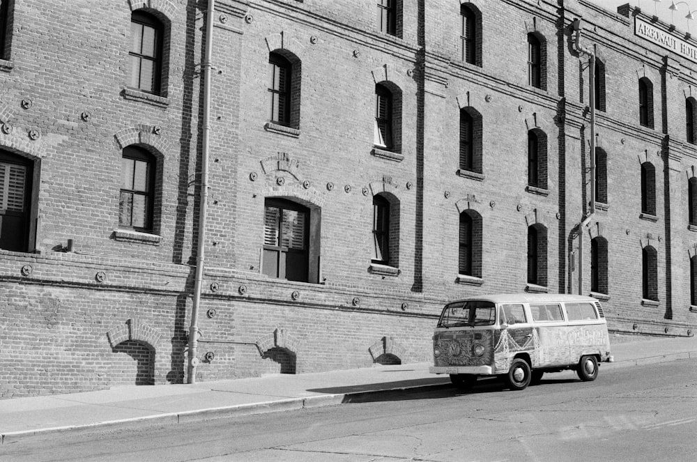 grayscale photo of a bus in front of a building