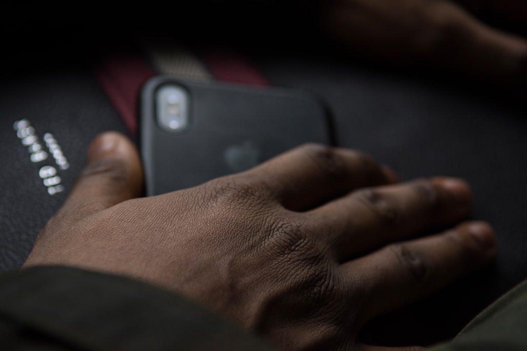 person holding black smartphone on black textile