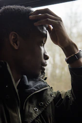 Close-up of a person staring blankly out a window, appearing lost in thought.