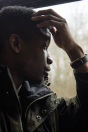 Close-up of a person staring blankly out a window, appearing lost in thought.