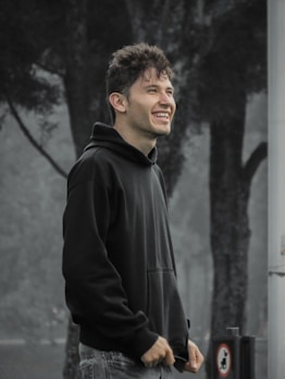 man in black zip up jacket standing near grey wall