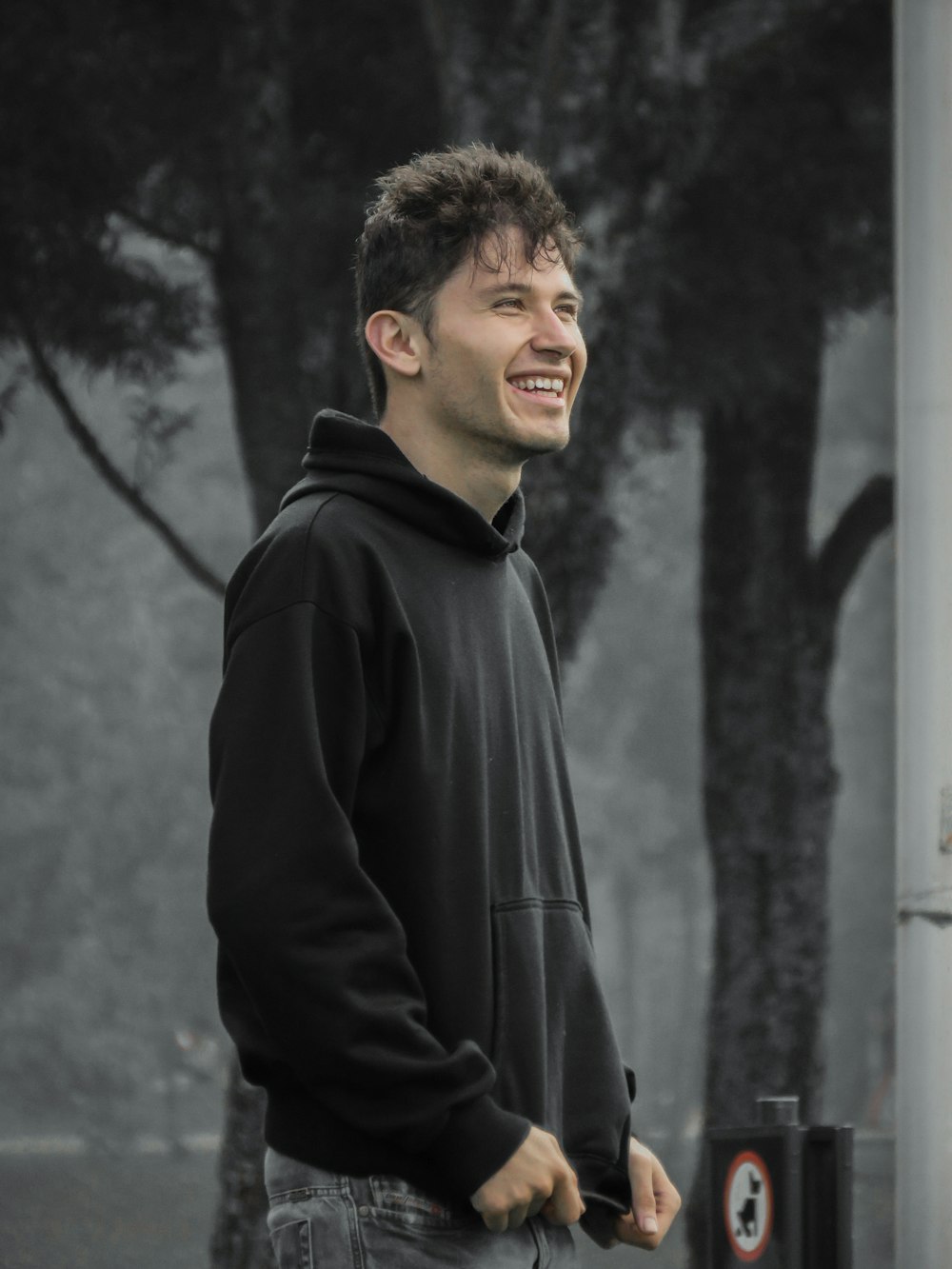 man in black zip up jacket standing near grey wall