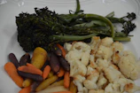 A vibrant plate of colorful roasted vegetables arranged artfully on a neutral green ceramic dish.