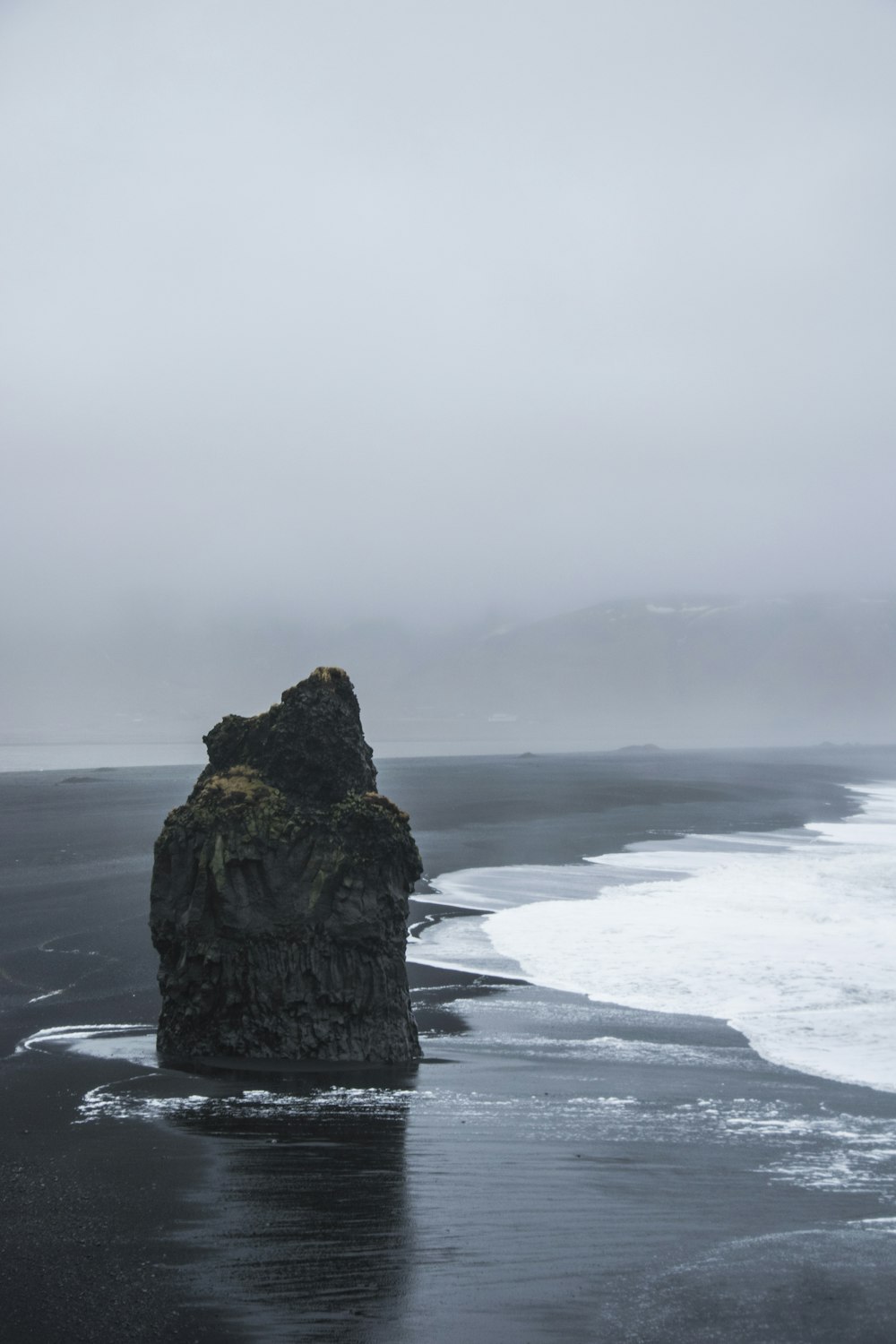 brown rock formation on sea under white clouds during daytime