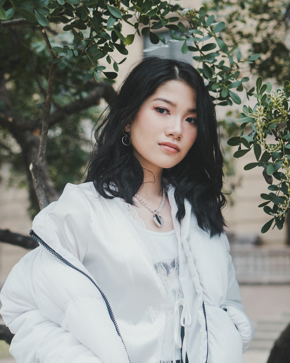 woman in white dress shirt standing under green tree during daytime