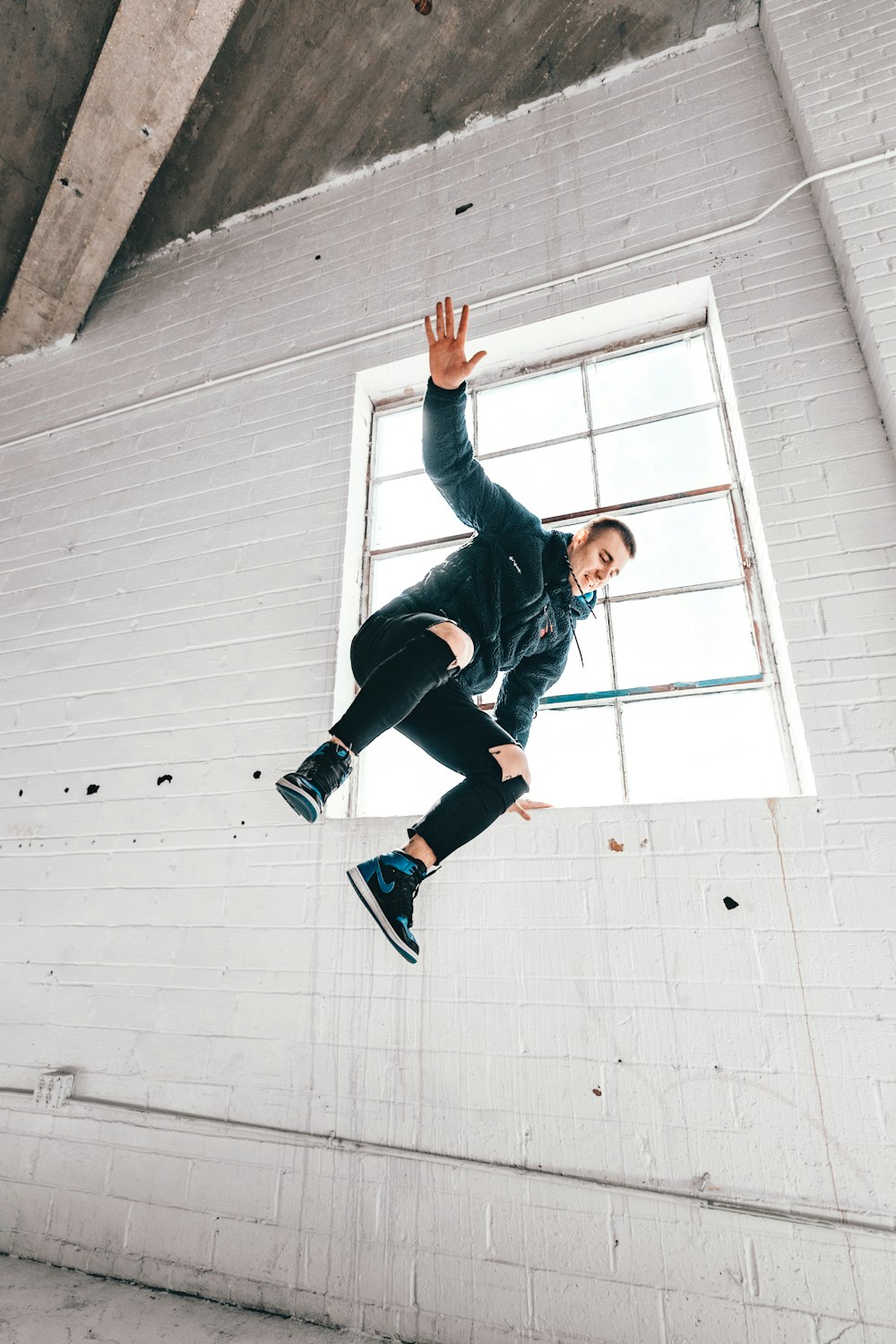 woman in black jacket and black pants jumping on white wall