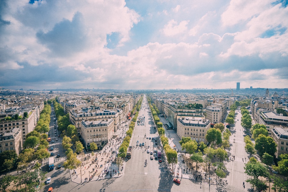 people walking on street near city buildings under blue and white sunny cloudy sky during daytime