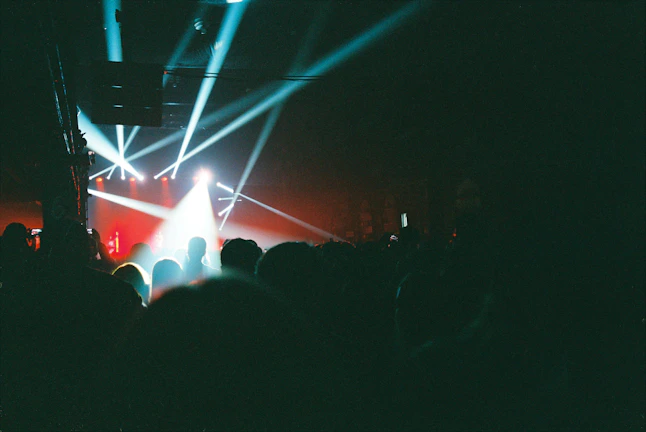 Crowd lit by neon lights enjoying an intense music concert under dark surroundings
