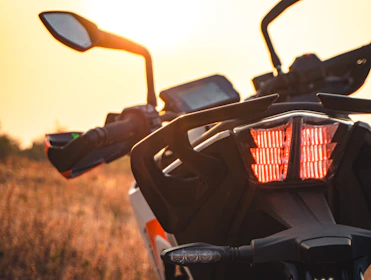 Close-up of a motorcycle helmet resting on a bike with a sunset background.