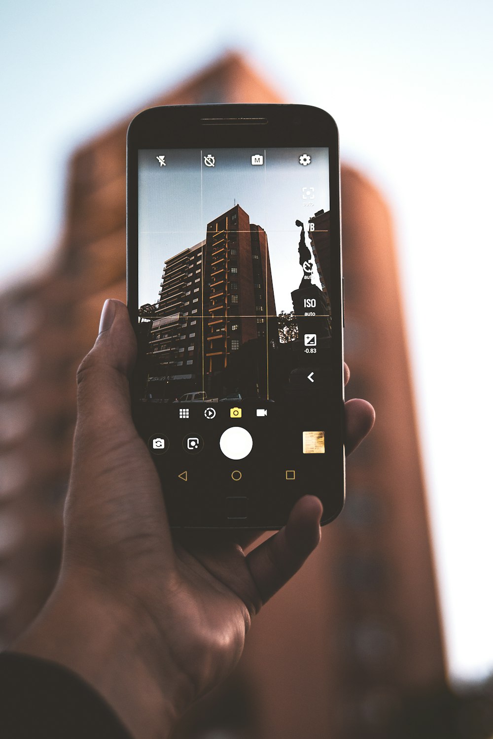 person holding black smartphone taking photo of brown building