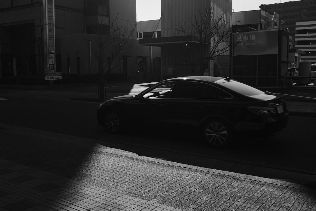 grayscale photo of black coupe on road