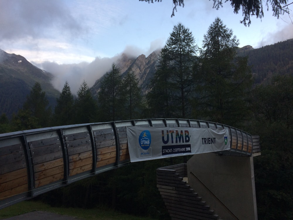 gray concrete bridge near green trees and mountain during daytime