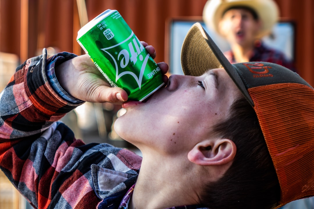 man drinking on green and white cup