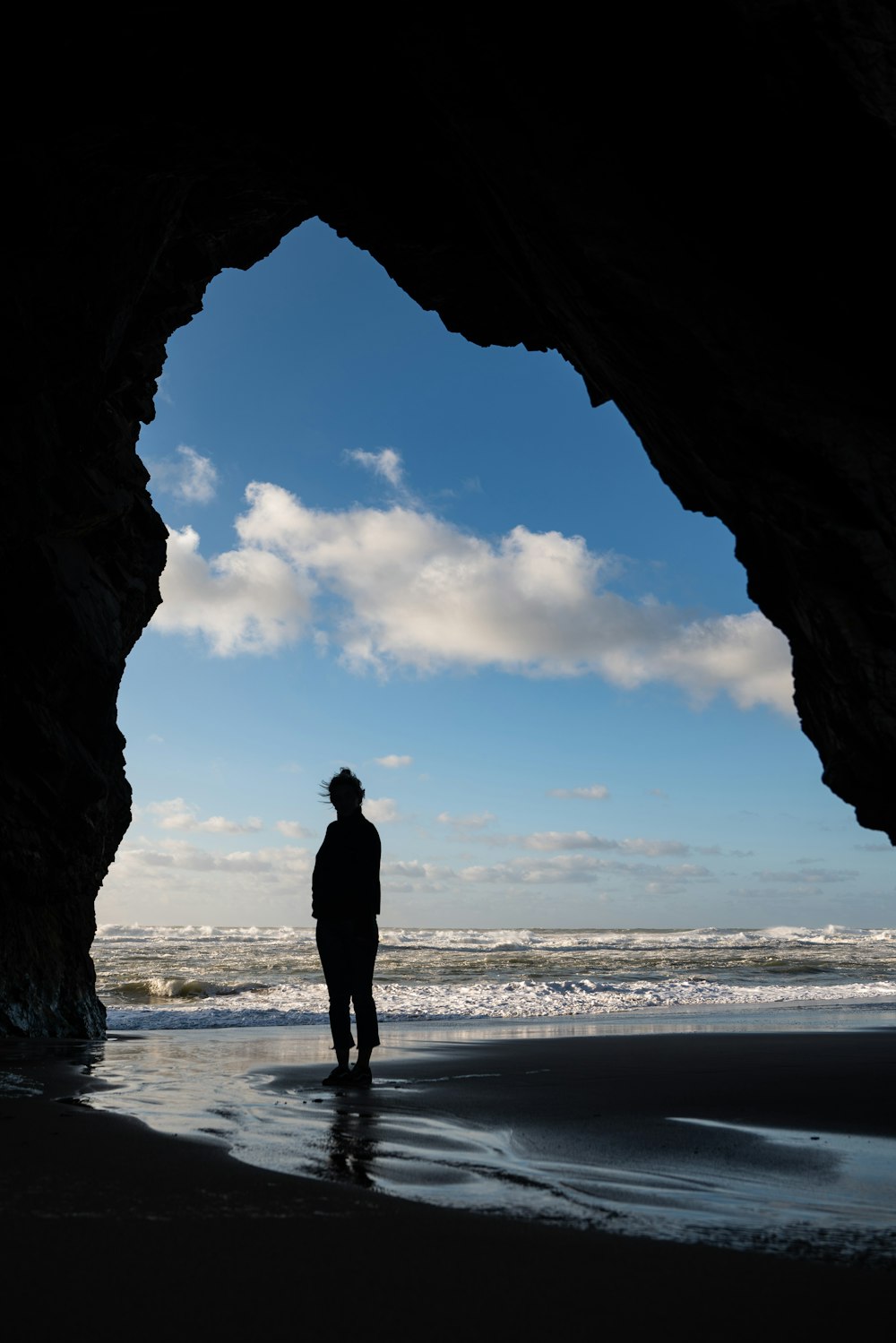 silhouette of man standing on seashore during daytime