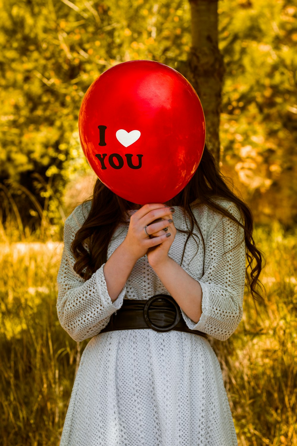 woman in gray sweater holding red balloon