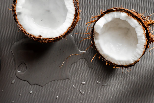 Fresh coconut halves and coconut products displayed on a cream-colored cloth.