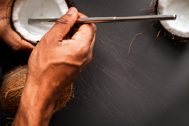 Hand holding a young coconut with a straw ready for drinking
