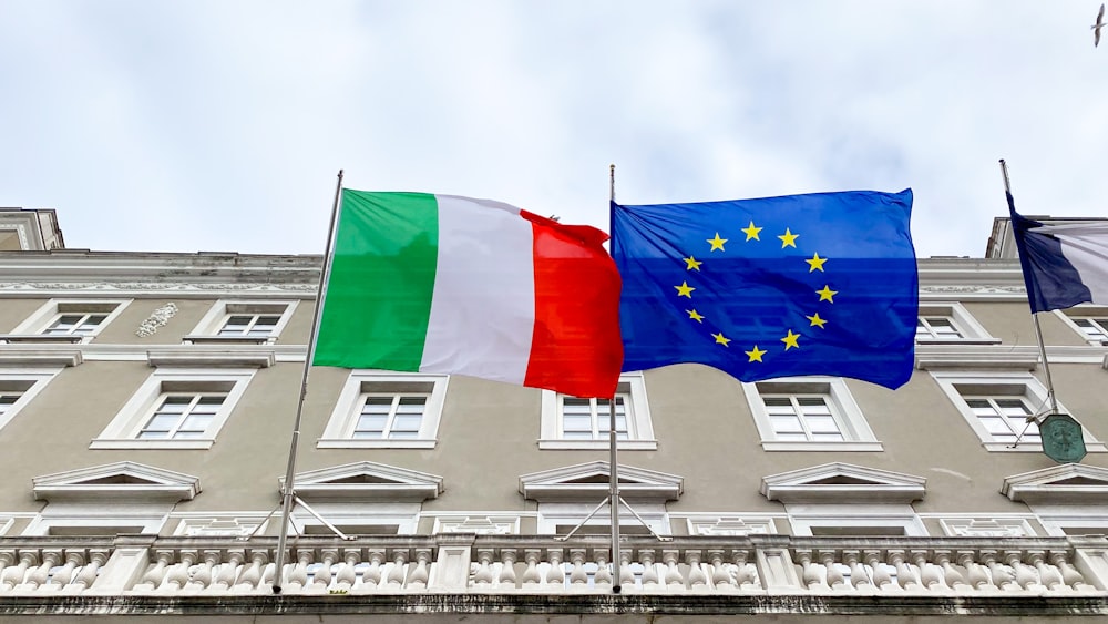 two flags are flying in front of a building