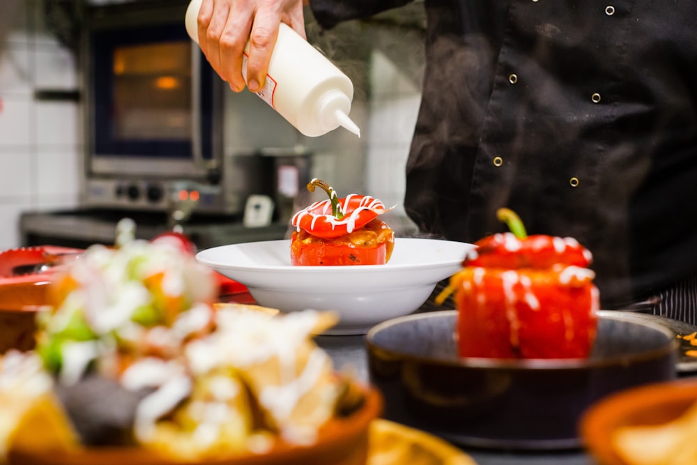 person holding white ceramic bowl with sliced strawberries