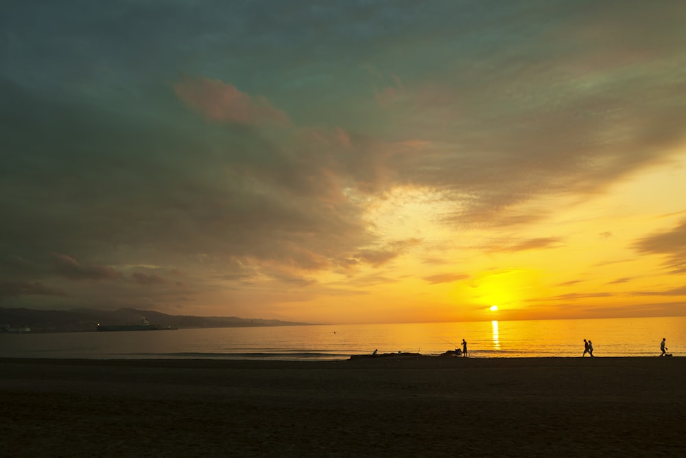 silhouette di persone sulla spiaggia durante il tramonto
