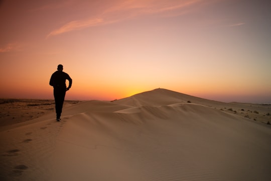 man in black jacket standing on desert during daytime in El Oued Algeria