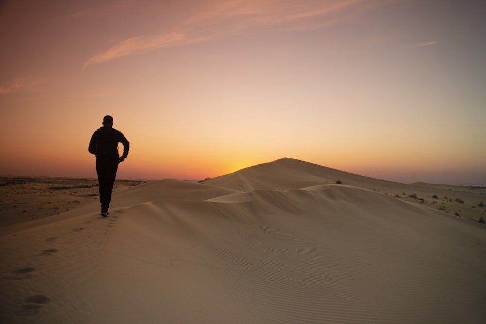 man in black jacket standing on desert during daytime