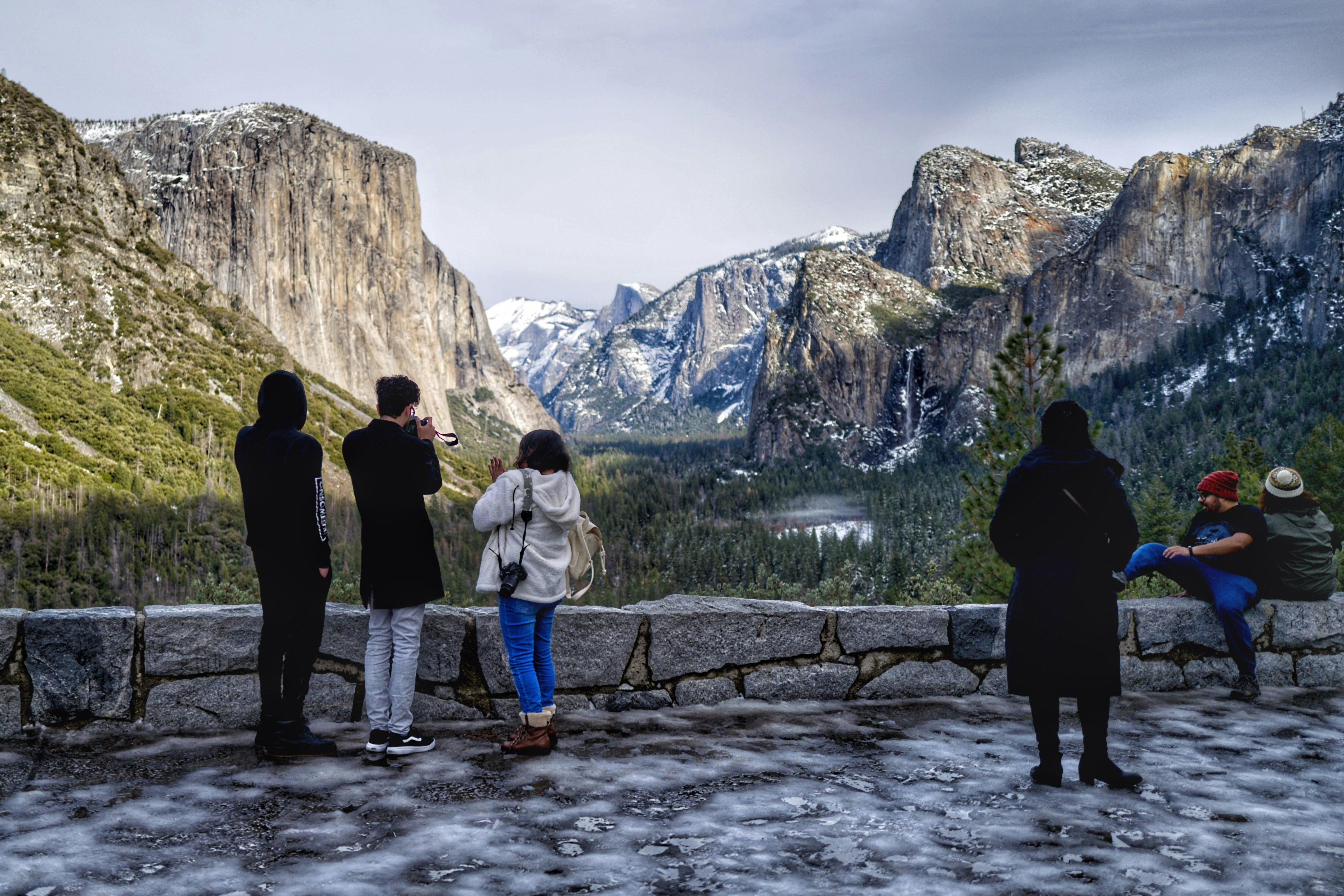 people walking on brown wooden bridge near brown rocky mountain during daytime