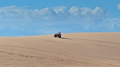 An adventurous rider navigating rugged desert trails on an ATV under a bright blue sky.
