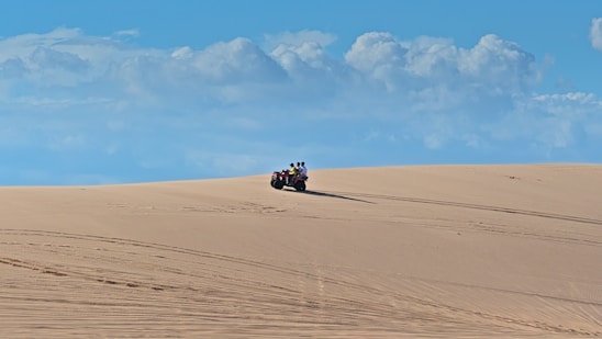 A rugged liwawind ATV racing across golden Liwa desert dunes under a clear blue sky.