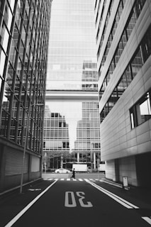 Greyscale photo of cars on road near building