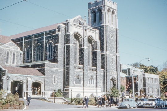 people walking near white concrete building during daytime in Timothy Eaton Memorial Church Canada