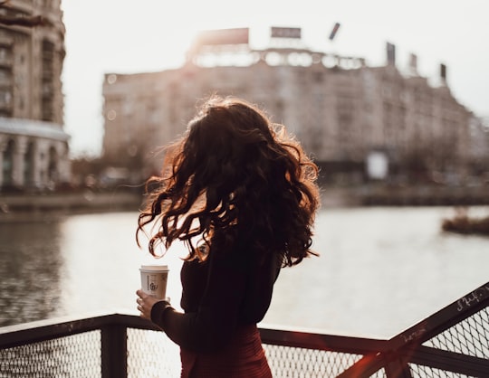 woman in red long sleeve shirt standing on bridge during daytime in Bucharest Romania