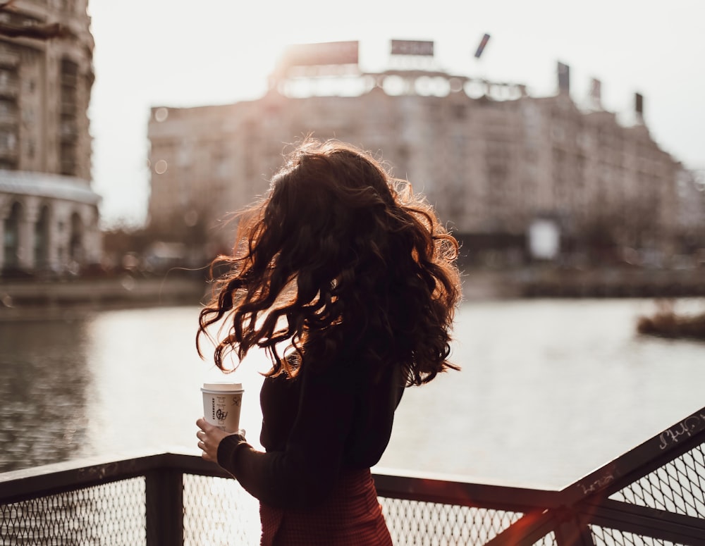 woman in red long sleeve shirt standing on bridge during daytime