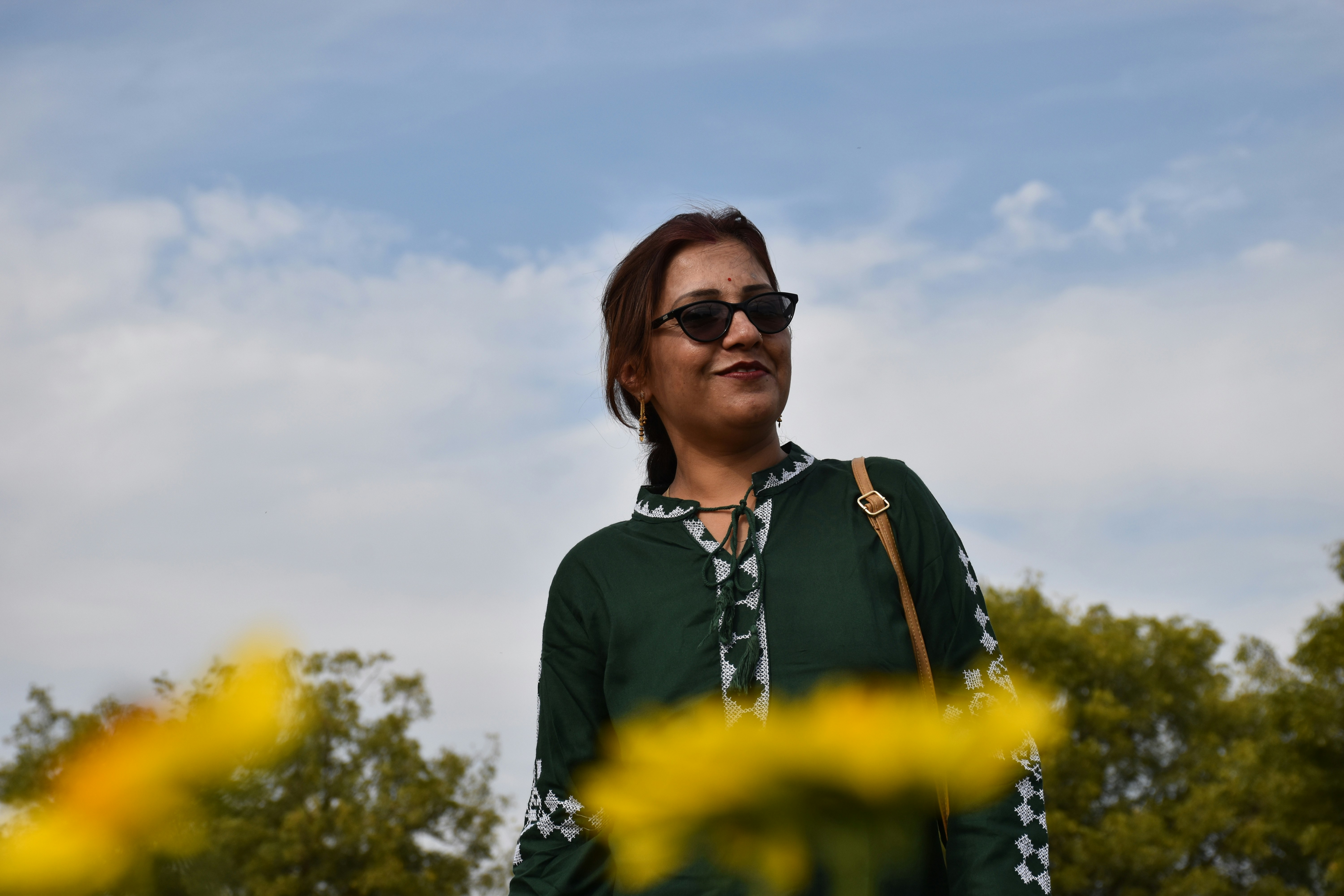 woman in black cardigan and black shirt standing on yellow flower field during daytime