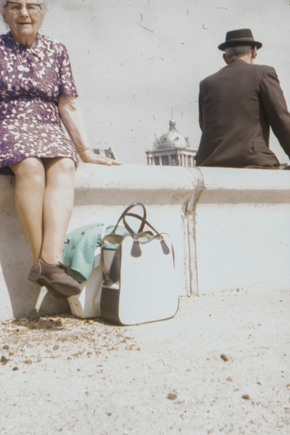 woman in purple and white floral dress sitting on white concrete bench